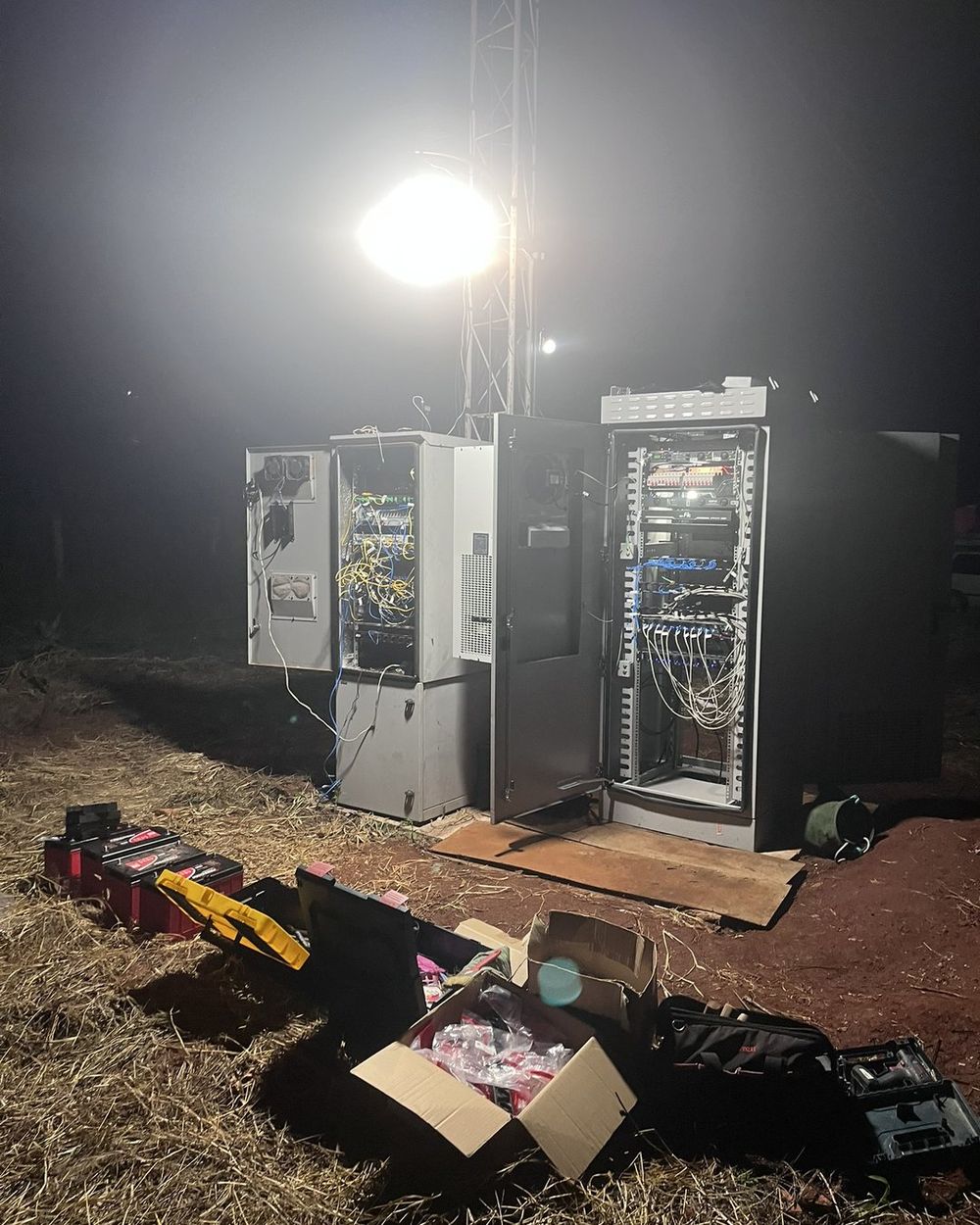 Site de telecom em obra à noite, sob refletor